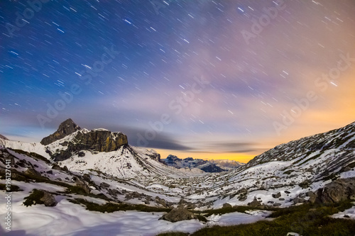 Starry night sky in snowy alpine mountains. Winter in Swiss Alps, Switzerland. photo