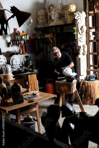 Senior man working on marble sculpture in his workshop with hammer and chisel. © Zoran Zeremski