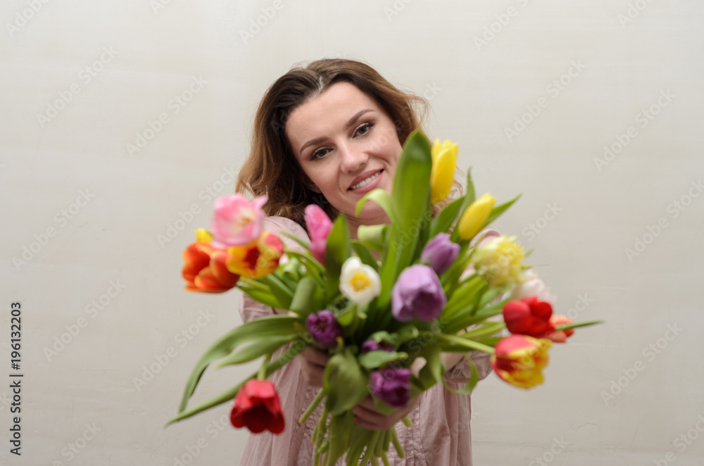 Young charming girl with a bouquet of flowers - multi-colored tulips