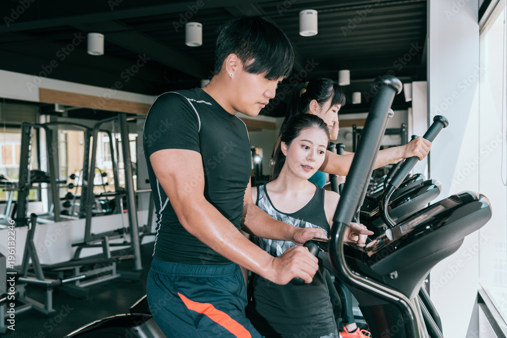 Man working out on elliptical machine with his trainer. Man working out on elliptical machine with his trainer.