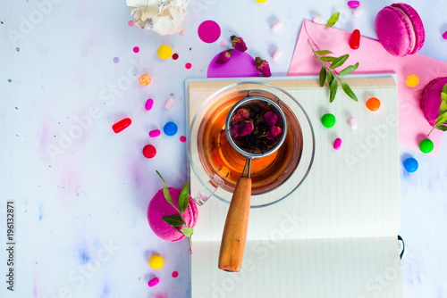 Feminine flat lay with tea, sweets and open book with empty pages. Colorful party background with confetti. Planning concept with copy space.