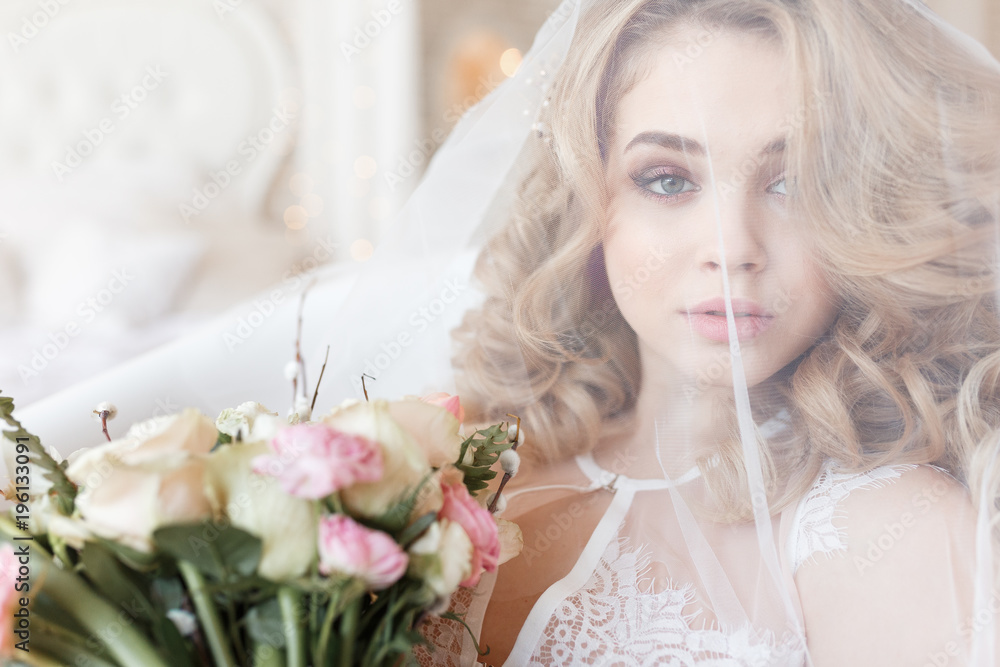 Tender portrait of a beautiful bride under a veil holding bouquet