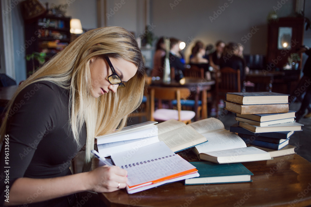 Blonde girl in the library, makes a summary of the textbooks. Education, exam preparation Blonde girl in the library, makes a summary of the textbooks. Education, exam preparation