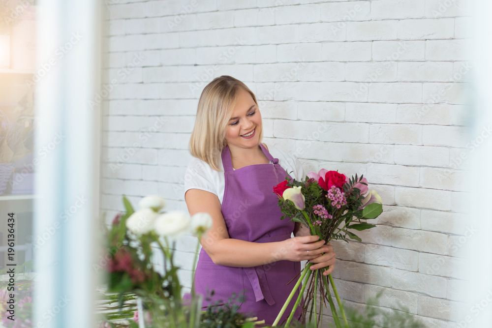 Portrait of smiling female florist with full of flower plants in shop. Woman creates a flower arrangement or composition for the Spring Festival or another holiday