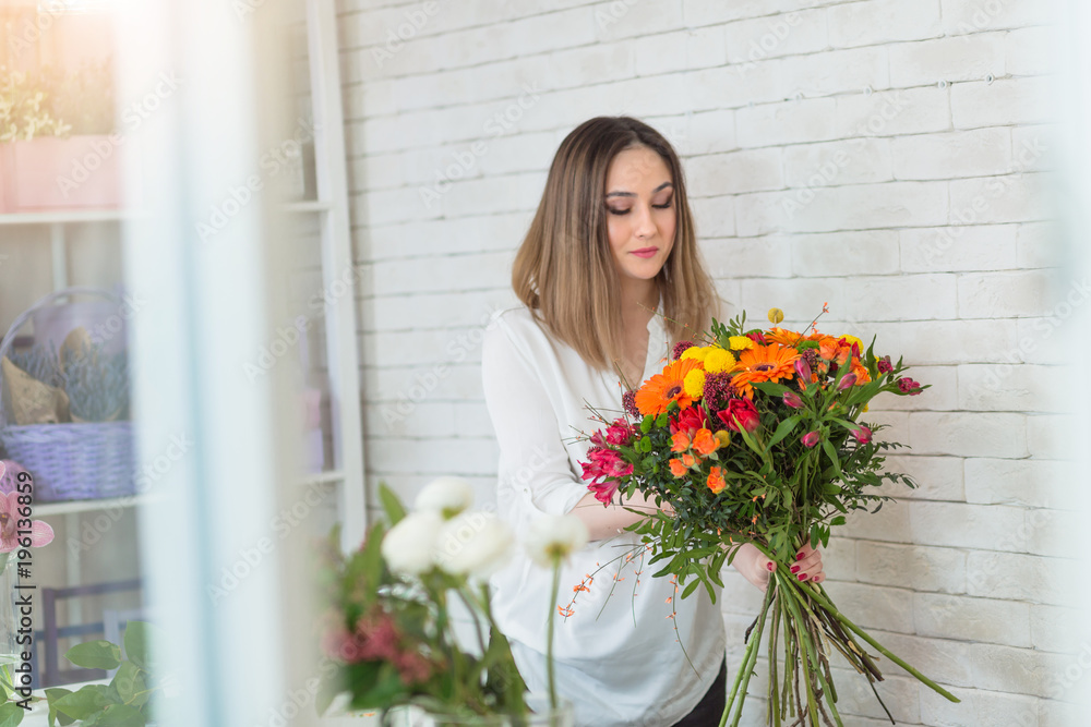 Female florist making fresh flowers bouquet composition in flower shop