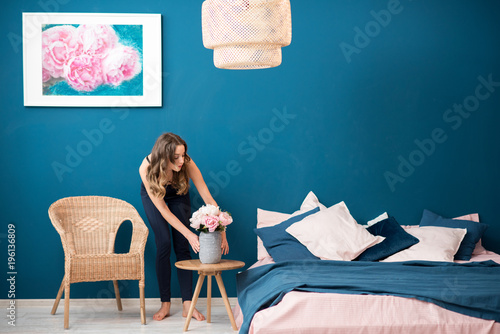 Young woman decorating bedroom with beautiful flowers at home photo