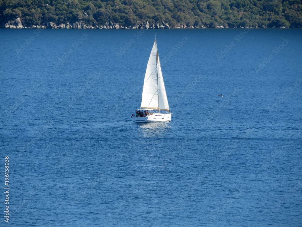 Sailboat in the sea. Yacht near mountainous forested shore
