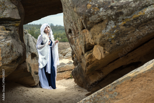 beautiful girl dressed as an elf princess. standing near the stone walls. Monument stone tomb photo