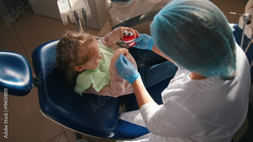 Girl on reception at the dentist, the stomatologist examines the child's teeth, cute and naughty girl smiling photo