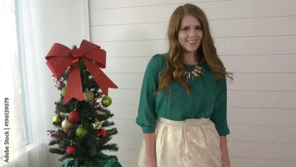 Woman twisting to show off her dress standing next to small christmas tree. Woman twisting to show off her dress standing next to small christmas tree.