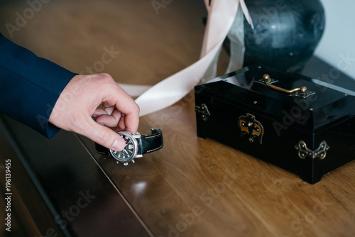 The bridegroom takes his watch in his hand.