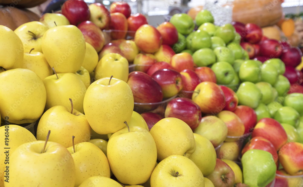 juicy apple background of yellow, red, green fruit for sale on the market