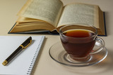 Tea, book and notebook on white table