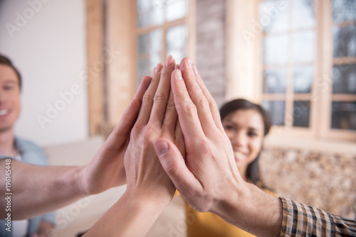 High five. Close up of hands of nice positive young people while giving each other high five