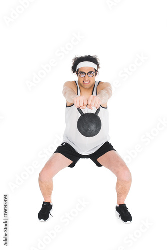 Skinny sportsman in eyeglasses holding kettlebell in hands isolated on white