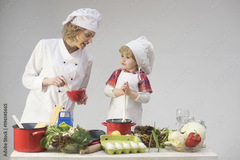 Mother teaches son to cook on light background. Mother teaches son to cook on light background.