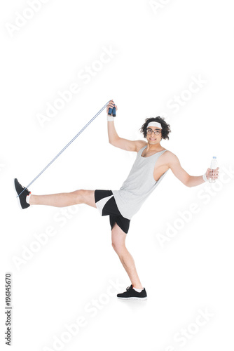 Skinny sportsman in eyeglasses with jump rope and bottle of water isolated on white