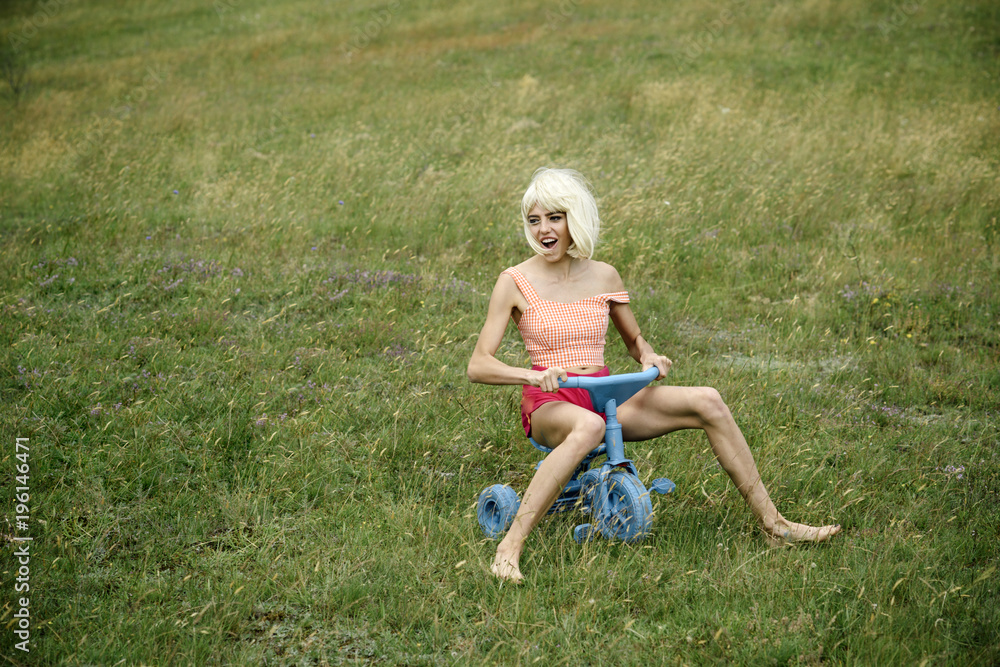 Happy woman play on toy bicycle in summer. Happy woman play on toy bicycle in summer.
