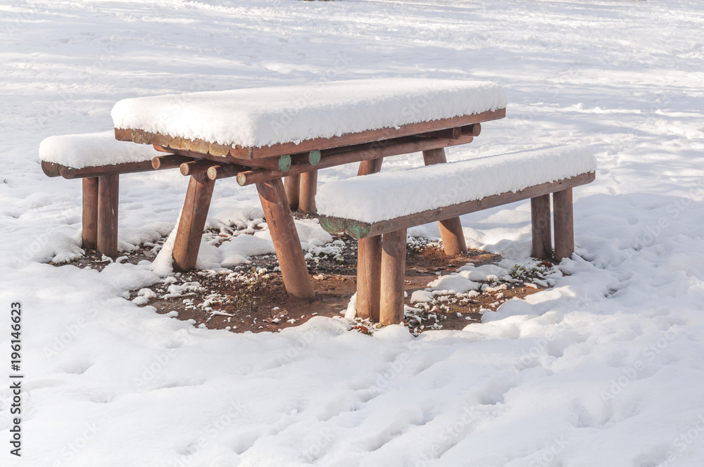 Wooden bench and table covered with snow in the city winter season