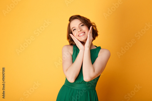 portrait of young pretty woman looking at camera isolated on orange