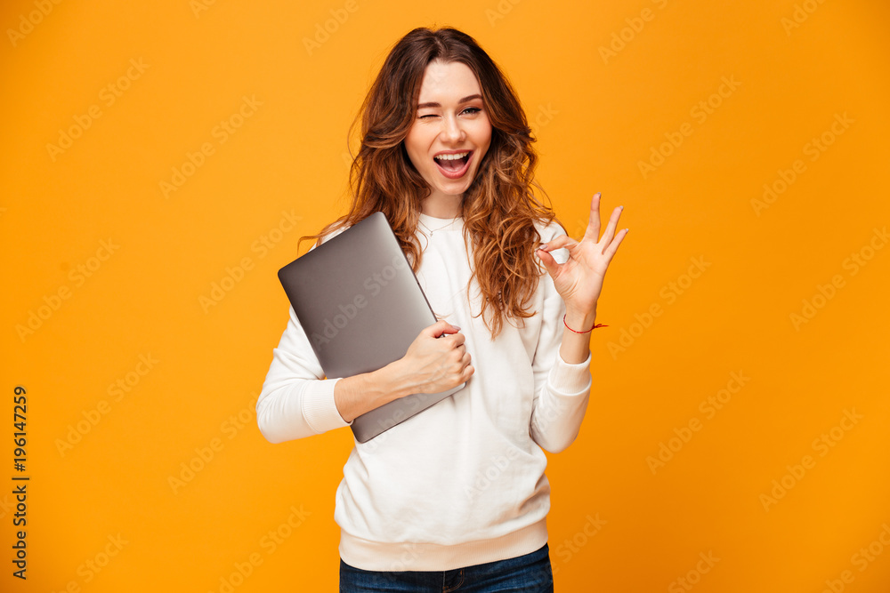 Cheerful brunette woman in sweater holding laptop computer Cheerful brunette woman in sweater holding laptop computer