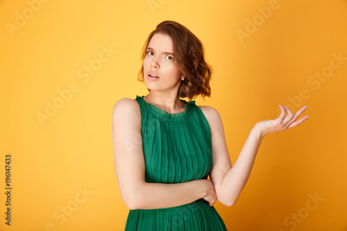 portrait of young confused woman isolated on orange