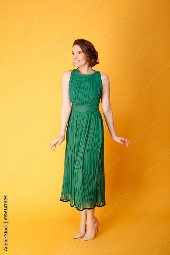 beautiful smiling woman in green dress posing isolated on orange beautiful smiling woman in green dress posing isolated on orange