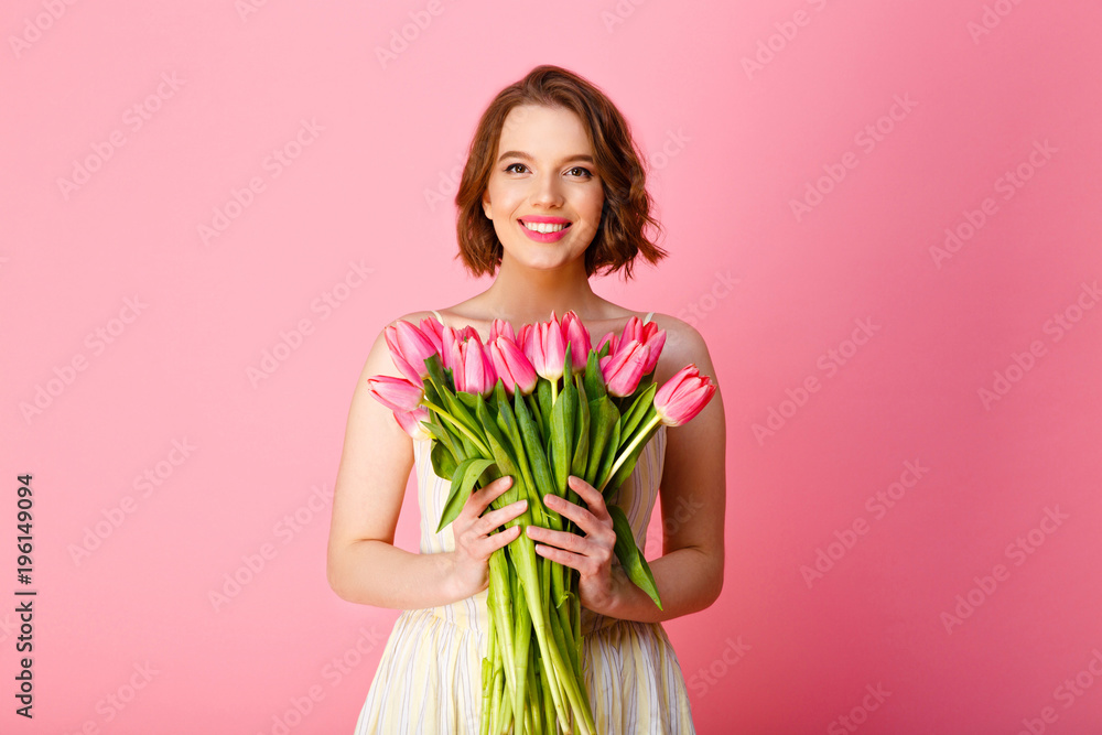 portrait of smiling woman with bouquet of pink tulips in hands isolated on pink portrait of smiling woman with bouquet of pink tulips in hands isolated on pink
