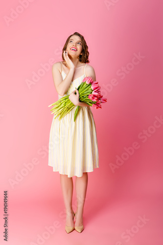 dreamy woman with bouquet of pink tulips isolated on pink