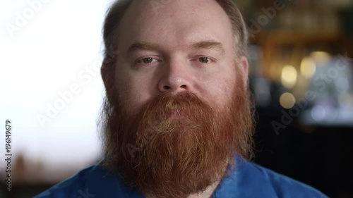 Black look on the face of man with red thick beard as he stares into the camera. photo