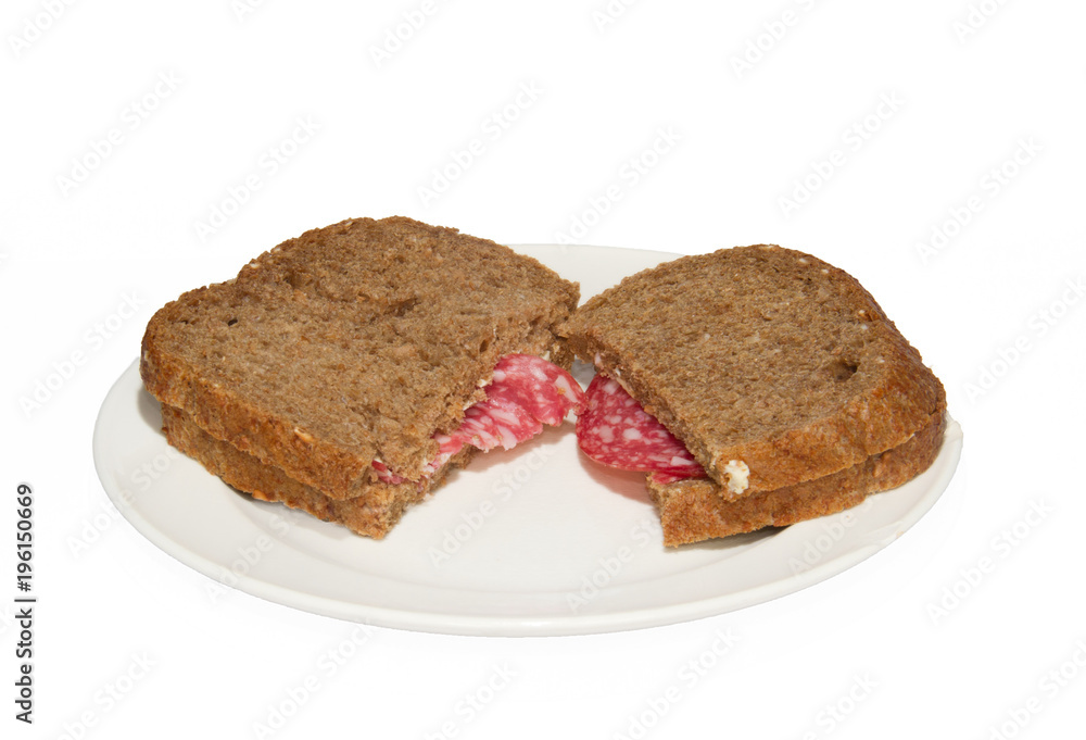 Two sandwiches of whole grain bread with slices of sausage on a white plate