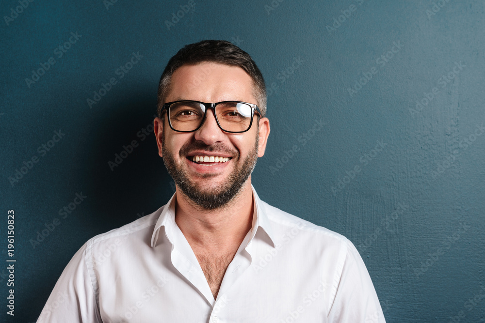 Image of smiling man standing over dark blue background Image of smiling man standing over dark blue background