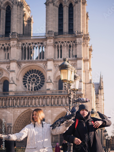 Tourists feeding pigeons in the square in front of the cathedral of Notre Dame © paulzhuk