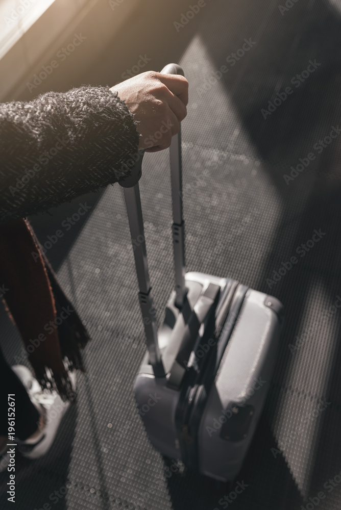 Close up of woman holding a suitcase in the airport.
