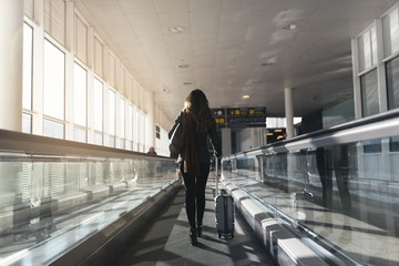 Unrecognizable woman walking with suitcase in the airport.