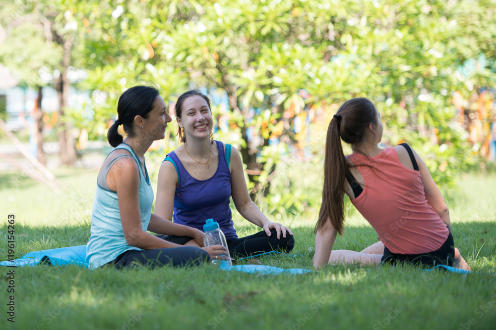 Families with young Russian mother and daughter are talk about exercise and Drink Water. After practice yoga at the park finished. Health and Fitness concept Families with young Russian mother and daughter are talk about exercise and Drink Water. After practice yoga at the park finished. Health and Fitness concept