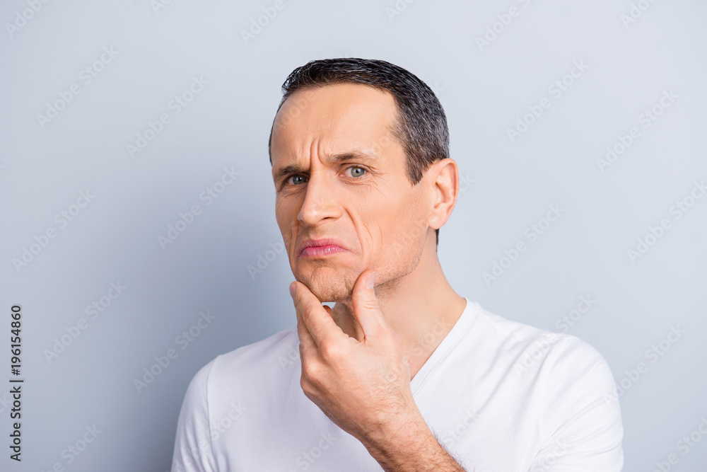 Portrait of trendy, experienced, neat, brunet, expertising, examine his face, looking at camera holding hand on chin with dislike expression, isolated on grey background, having problem with skin Portrait of trendy, experienced, neat, brunet, expertising, examine his face, looking at camera holding hand on chin with dislike expression, isolated on grey background, having problem with skin