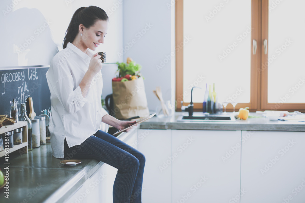 Portrait of young woman standing against kitchen background. Portrait of young woman standing against kitchen background.