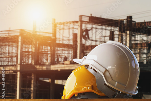 white and yellow safety helmet in construction side with sunset photo