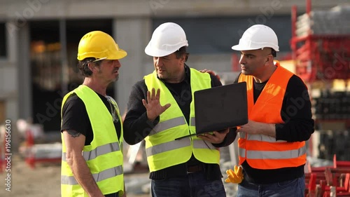 Construction site manager giving instructions using a laptop digital computer