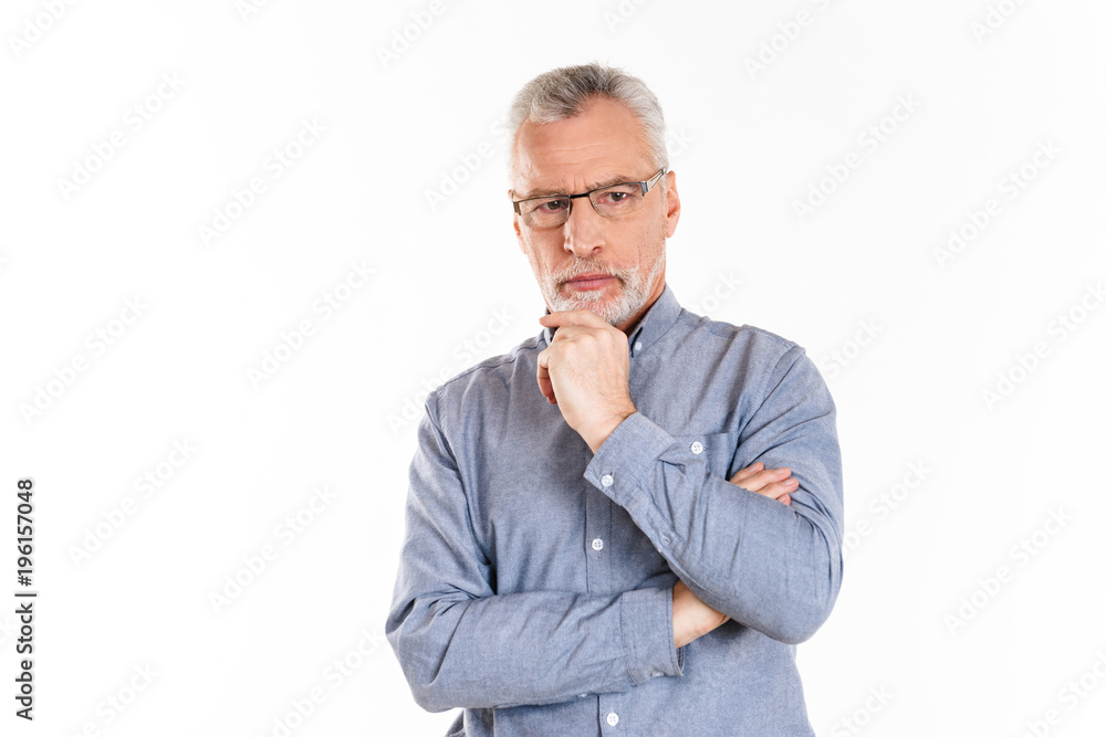 Portrait of serious confident man looking aside with folded hands