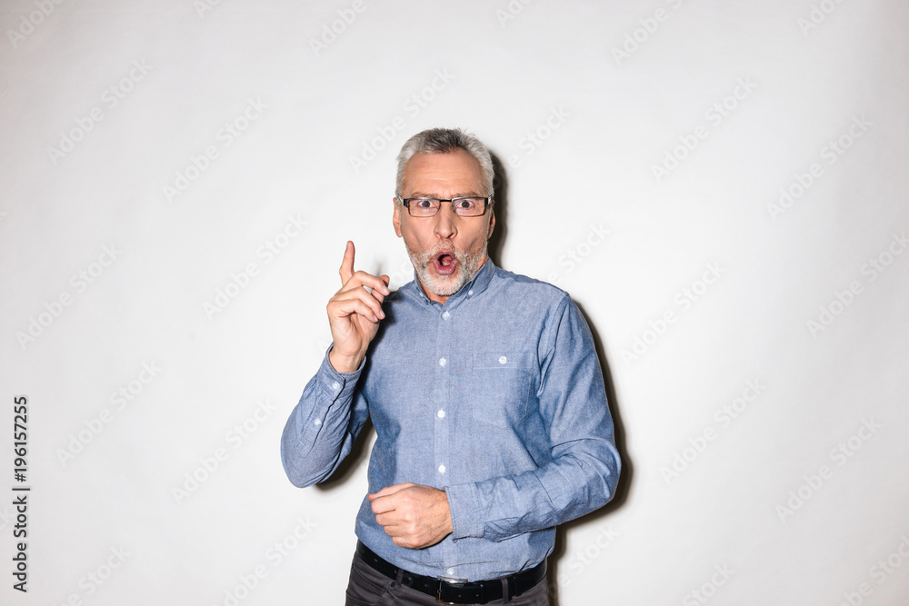 Surprised man looking camera with opened mouth and pointing up with finger Surprised man looking camera with opened mouth and pointing up with finger
