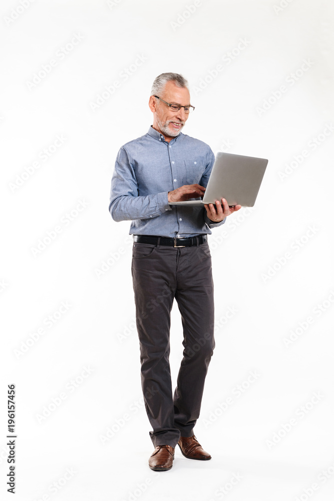 Cheerful mature man in eyeglasses using laptop computer Cheerful mature man in eyeglasses using laptop computer