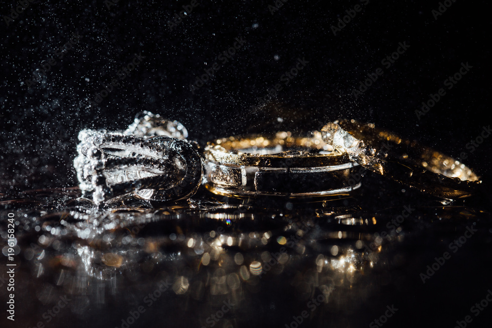 Wedding rings and earrings are wet, with drops. Reflections on the glass are professional. Wedding rings and earrings are wet, with drops. Reflections on the glass are professional.