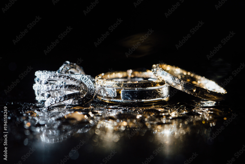 Wedding rings and earrings are wet, with drops. Reflections on the glass are professional. Wedding rings and earrings are wet, with drops. Reflections on the glass are professional.