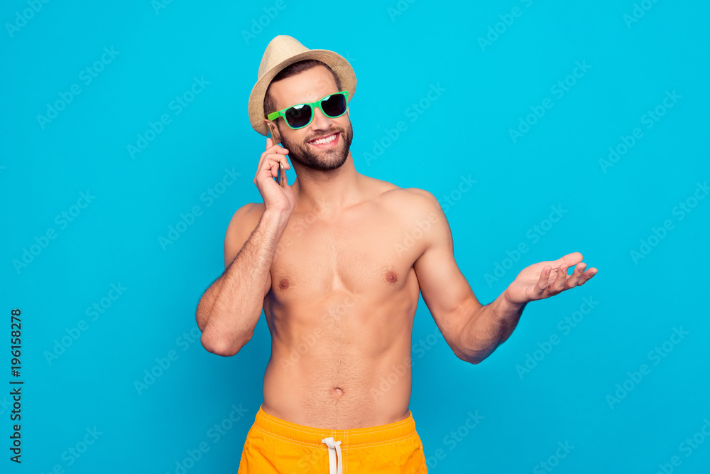 Cheerful, glad, attractive bachelor, ladies' man holding smart phone near ear, talking with friends, gesturing, showing something with hand, telling about his holidays over blue background Cheerful, glad, attractive bachelor, ladies' man holding smart phone near ear, talking with friends, gesturing, showing something with hand, telling about his holidays over blue background