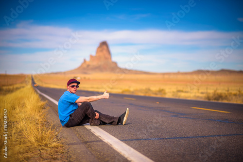 Tired hitch-hiker sitting on a road