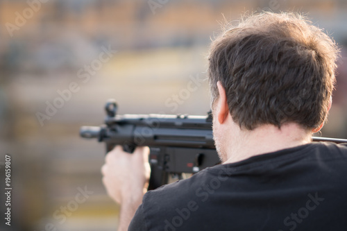 Back turned caucasian man holding a sniper rifle