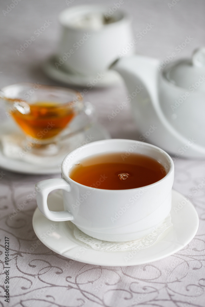 White cup of tea with honey on a white background with teapot. Serving tea. Honey in Saucer. White cup of tea with honey on a white background with teapot. Serving tea. Honey in Saucer.