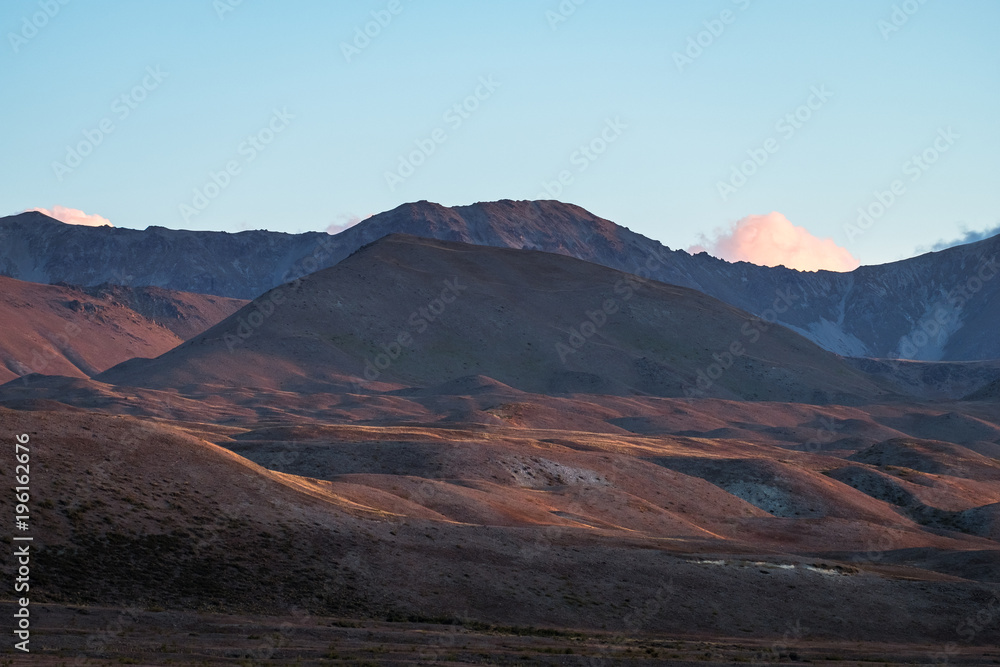 Fototapeta premium Beautiful colorful grassland mountain with blue sky at sunset.
